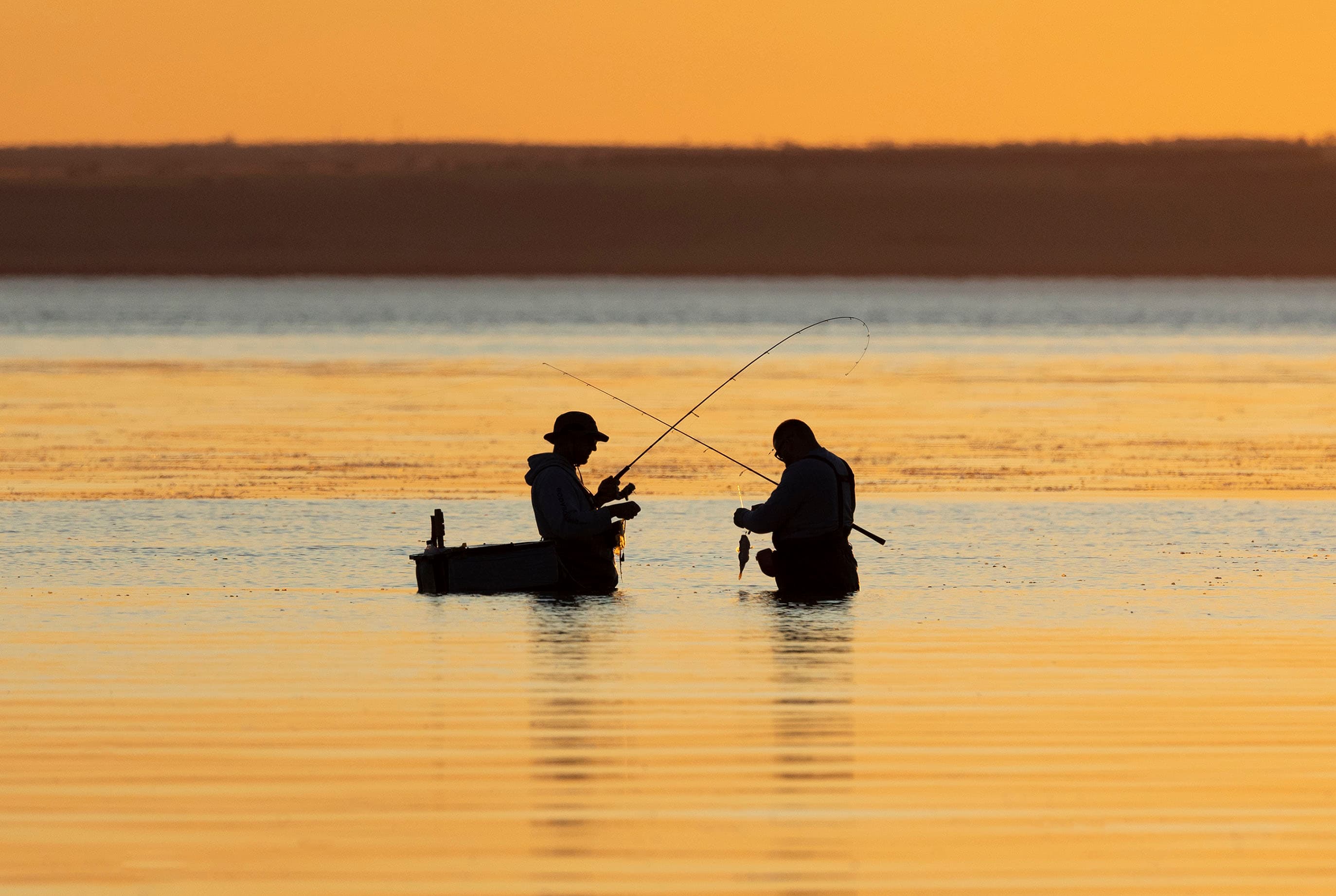 A couple of fishers at sunset at Bald Hill Beach, South Australia.